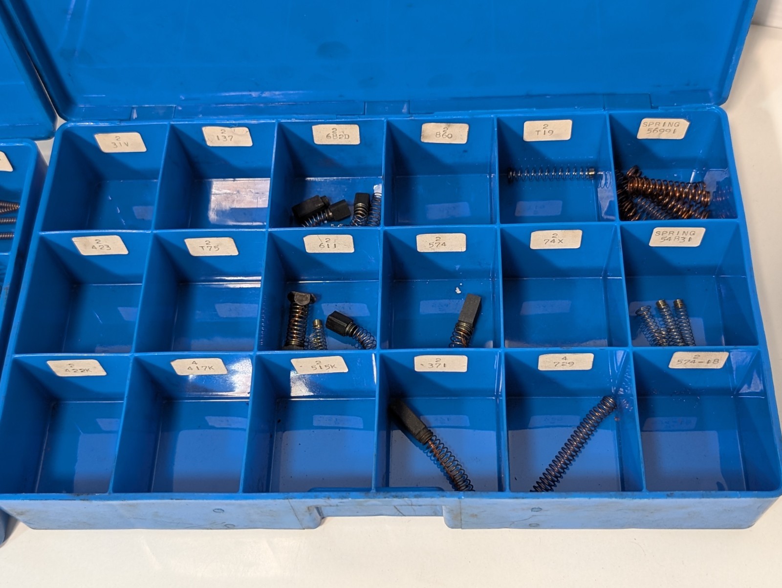 Large lot of assorted motor brushes as shown, two blue organizers included